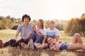 Outdoor shot of cheerful youth couples enjoy togetherness and spare time during summer day or weekend, sit closely to each other,