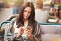 Outdoor shot of concentrated serious young female holds mobile phone in hand, types message to boyfriend, surfes social network or