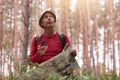 Outdoor shot of eldery man hiking and looking up at sky, holding compass and map in hands, try to find right way, having active