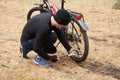 Outdoor shot of man repairing his bicycle in field or forest, sitting on ground, pumping up tire with special equipment, being Royalty Free Stock Photo