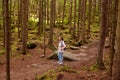 Outdoor shot og young girl walks alone in forest, woman in ight jacket happily walks, being among trees, likes to spend time in Royalty Free Stock Photo