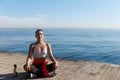 Outdoor shot of peaceful fitness woman sitting in asana and doing yoga near the sea. Female athlete meditating on Royalty Free Stock Photo