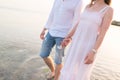 Outdoor shot of romantic young couple walking along the sea shore holding hands. Royalty Free Stock Photo
