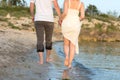 Outdoor shot of romantic young couple walking along the sea shore holding hands Royalty Free Stock Photo