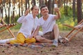 Outdoor shot of smiling couple sitting in the forest and broadcasting livestream or having video call, husband and wife making