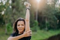 Outdoor shot of sporty European woman has dark hair raises arm with dumbbell, trains muscles and looks somewhere into distance,