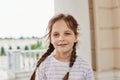 Outdoor shot of sweet charming cute little girl smiling looking at camera wearing striped shirt and having pigtails spending time Royalty Free Stock Photo