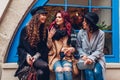 Outdoor shot of three young women chatting and laughing on city street. Best friends talking and having fun by cafe Royalty Free Stock Photo