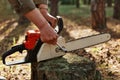 Outdoor shot of unknown person worker fixing chainsaw before or after deforestation, logger fixing tool for cutting trees,