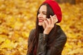 Outdoor shot of young attractive woman in autumn park using her phone for conversation with her boyfriendor hasband, being in good