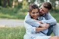 Outdoor shot of young happy couple in love sitting on grass on nature. Man and woman hugging  sunlight in summer park. Happy Royalty Free Stock Photo