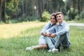 Outdoor shot of young happy couple in love sitting on grass on nature. Man and woman hugging, sunlight in summer park. Happy Royalty Free Stock Photo