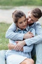 Outdoor shot of young happy couple in love sitting on grass on nature. Man and woman hugging, sunlight in summer park. Happy Royalty Free Stock Photo