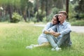 Outdoor shot of young happy couple in love sitting on grass on nature. Man and woman hugging, sunlight in summer park. Happy Royalty Free Stock Photo