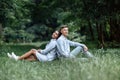 Outdoor shot of young happy couple in love sitting on grass on nature. Man and woman hugging, sunlight in summer park. Happy Royalty Free Stock Photo