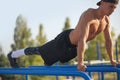 Outdoor shot of young muscular male doing pull ups exercises on horizontal bar outdoors. Happy athletic runner training hard at Royalty Free Stock Photo