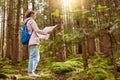 Outdoor shot of young slender backpacker being inspired by travelling, enjoying active rest, holding map, following trip way, good