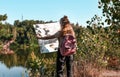 Outdoor shot of young slender backpacker being inspired by travelling, enjoying active rest, holding map, following trip way, good