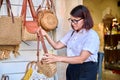 Outdoor showcase with woven knitted bags. Woman shopper choosing a bag.