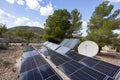 Outdoor solar panel array and satellite dish in rural landscape Royalty Free Stock Photo
