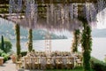 An outdoor space with dining tables and chairs, adorned with flowers hanging from the ceiling, A serene lakeside wedding under a Royalty Free Stock Photo