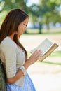 Outdoor splendor. a beautiful young woman reading a book while leaning against a tree trunk. Royalty Free Stock Photo