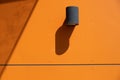 Outdoor spotlight lamp mounted on orange wall.