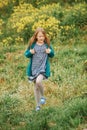 Outdoor spring portrait of cute 6-7 year old girl playing in yellow flowers field Royalty Free Stock Photo