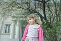 Outdoor spring portrait of daydreaming preschooler girl at blooming fruit tree and porch background