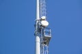 Outdoor stadium lights and telecommunication tower against daytime blue sky. Royalty Free Stock Photo