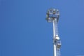 Outdoor stadium lights and telecommunication tower against daytime blue sky. Royalty Free Stock Photo