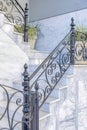 Outdoor staircase with black wrought iron railings and marble steps and wall