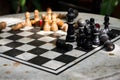 Outdoor stone chessboard with black and yellow figures. Competition and strategy concept. Chess wooden pieces on board in sunlight Royalty Free Stock Photo