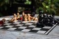 Outdoor stone chessboard with black and yellow figures. Competition and strategy concept. Chess wooden pieces on board in sunlight Royalty Free Stock Photo