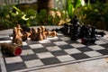 Outdoor stone chessboard with black and yellow figures. Competition and strategy concept. Chess wooden pieces on board in sunlight Royalty Free Stock Photo