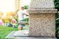 Outdoor stone stove with grill and skewers. Company of friends at barbecue party at park or backyard with green grass lawn and Royalty Free Stock Photo