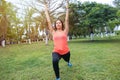 Outdoor stretching. Beautiful sportswoman working out in the park. Young brunette doing pilates