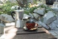 Outdoor summer breakfast with cup of coffee made with geyser coffeemaker and cookie stand on old wooden table in summer garden. Royalty Free Stock Photo