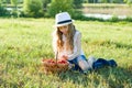 Outdoor summer portrait of little girl with basket strawberries, straw hat. Nature background, rural landscape, green meadow, coun Royalty Free Stock Photo