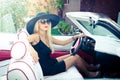 Outdoor summer portrait of stylish blonde vintage woman driving a convertible retro car. Fashionable attractive fair hair female Royalty Free Stock Photo