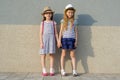 Outdoor summer portrait of two happy girl friends 7, 8 years holding hands. Girls in striped dresses, hats with backpack, Royalty Free Stock Photo