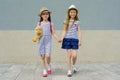 Outdoor summer portrait of two happy girl friends 7, 8 years holding hands. Girls in striped dresses, hats with backpack, Royalty Free Stock Photo