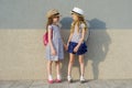 Outdoor summer portrait of two happy girl friends 7,8 years in profile talking and laughing. Girls in striped dresses, hats with