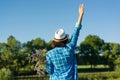 Outdoor summer portrait of woman with bouquet of wildflowers, straw hat. View from the back, female raised her hand. Royalty Free Stock Photo