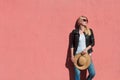 Outdoor summer portrait of young blonde woman in black leather jacket and white t shirt with sunglasses hold hat in hands against Royalty Free Stock Photo