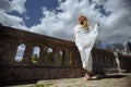 Outdoor summer portrait of young pretty cute girl. Beautiful woman posing at old bridge. in white dess standing near stone railin Royalty Free Stock Photo