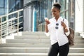 African american woman with backpack walking outdoor and talking on mobile phone Royalty Free Stock Photo