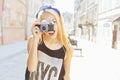 Outdoor summer smiling lifestyle portrait of pretty young woman having fun in the city in Europe with camera. Travel photo of phot