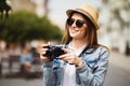 Outdoor summer smiling lifestyle portrait of pretty young woman having fun in the city in Europe in evening with camera travel pho Royalty Free Stock Photo