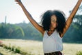 Outdoor sunny portrait of the adorable active african girl with green eye shadows and pretty smile dancing and enjoying